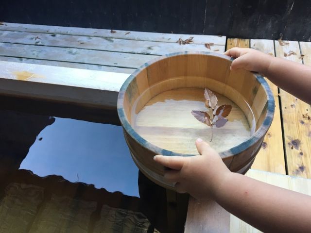 露天風呂で温泉の湯を汲む子供